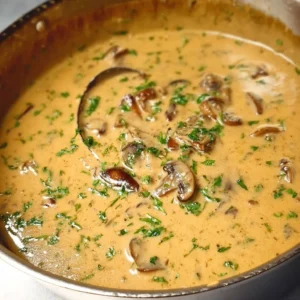 A bowl of rich and creamy homemade cream of mushroom soup garnished with herbs.